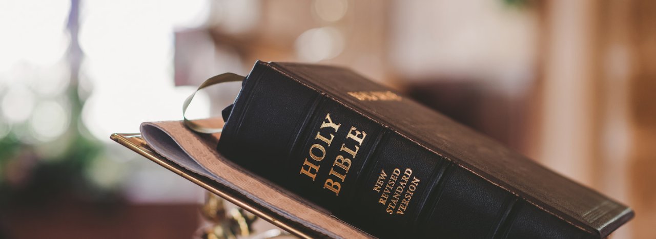 A black bible of the New revised standard version, resting on a lectern.