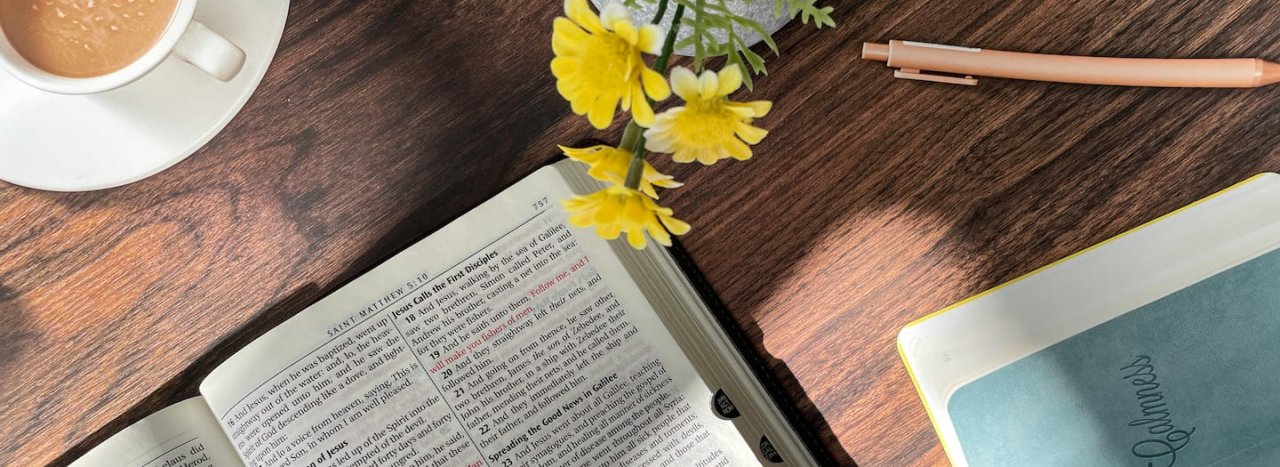 A Bible, cup of coffee, a flower in a vase, a pen and a notebook laid out, representing the holistic approach to learning at All Nations.
