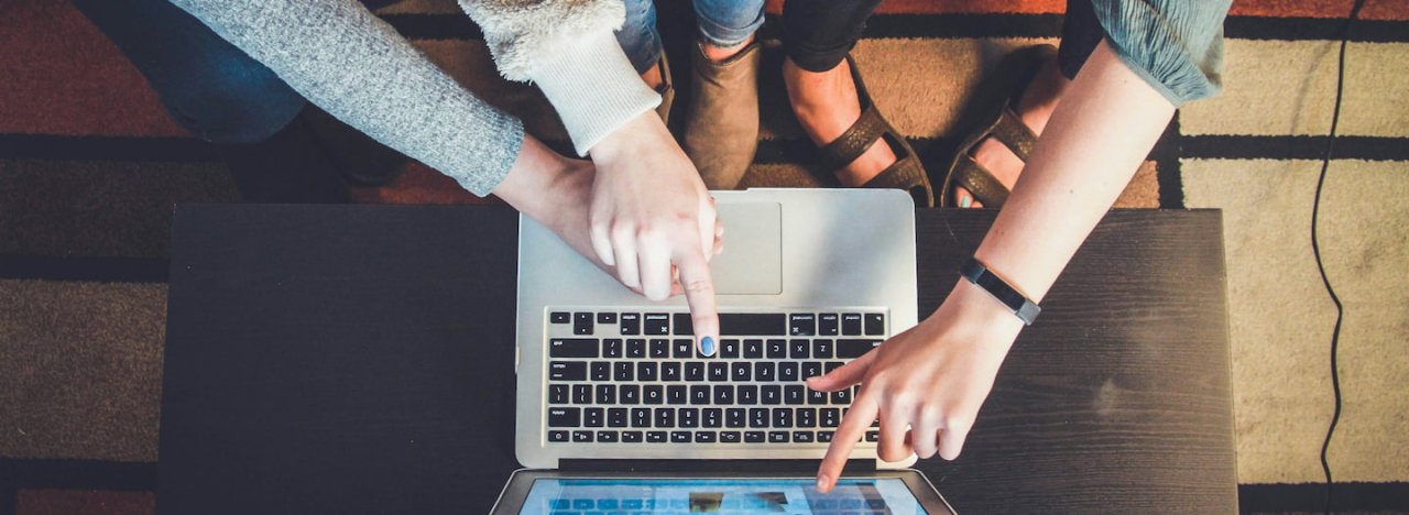 different hands pointing or clicking at a screen of a laptop, representing communities of practice (CoPs), online groups which run with Redcliffe College at All Nations.