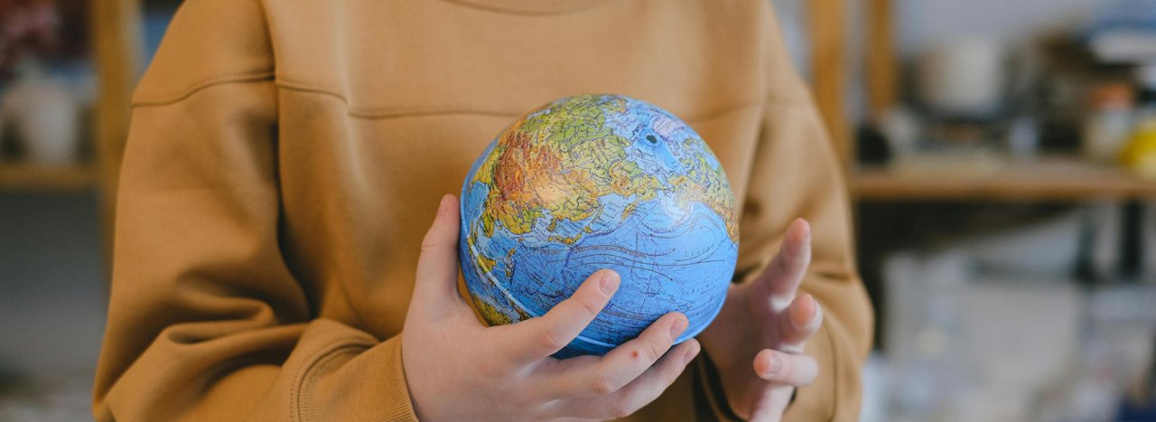 A person holding a blue globe in their hands, symbolising the Enable All fund appeal which helps students at All Nations financially.