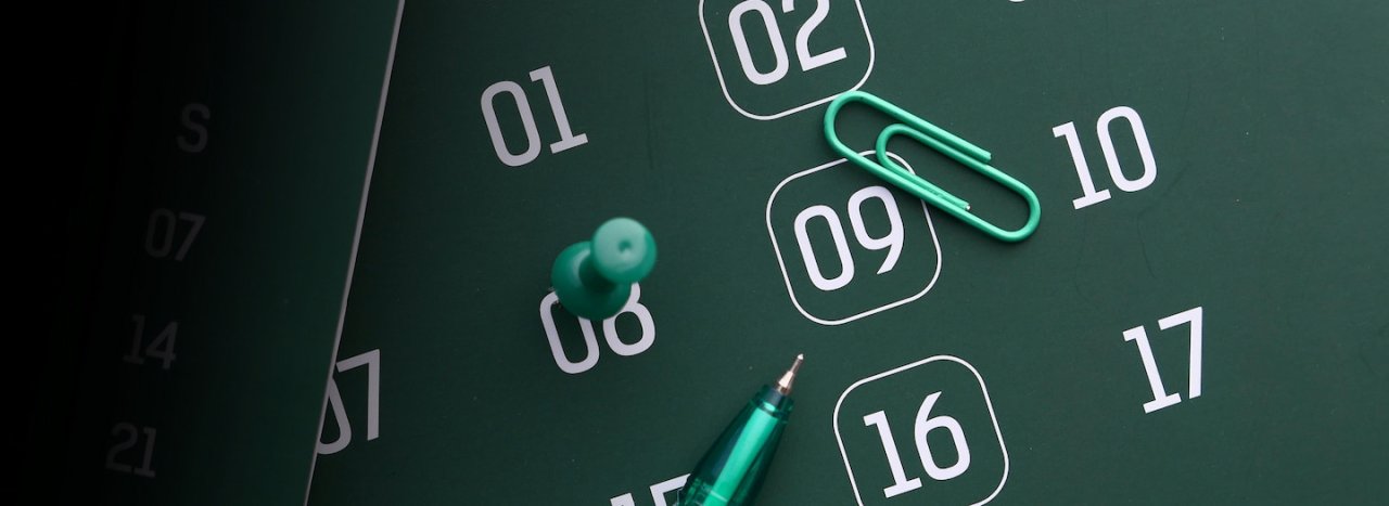 A stylized calendar with white numbers on a green background, a pin, pen and paper clip, representing term dates at All Nations college.